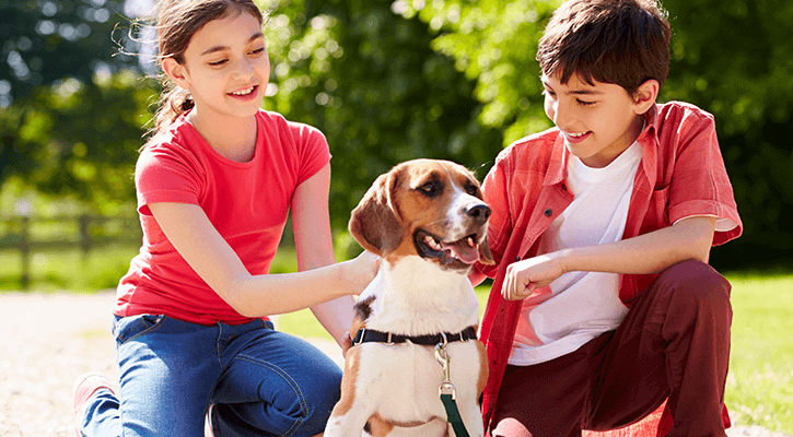 two kids sitting outside with their dog